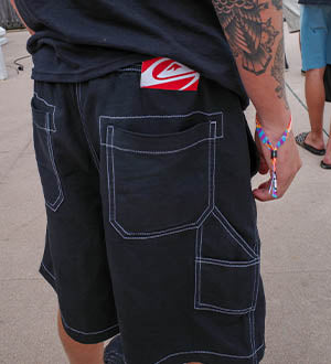 Person wearing black shorts with a red Quiksilver logo on the pocket.