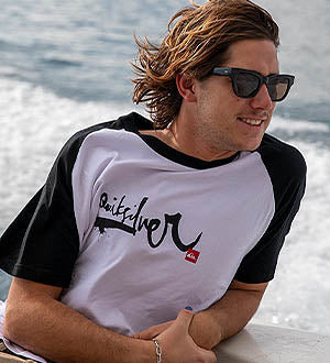 Man wearing a black and white T-Shirt by the water.